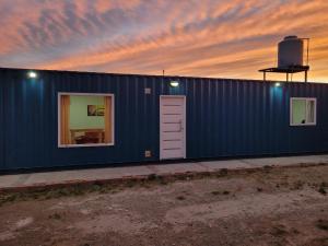 a blue building with a sunset in the background at Departamento Desire in Puerto Deseado