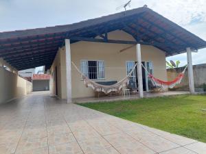 une maison avec une terrasse couverte dotée de hamacs dans l'établissement Casa Aconchego - piscina com hidromassagem, à Guaratuba