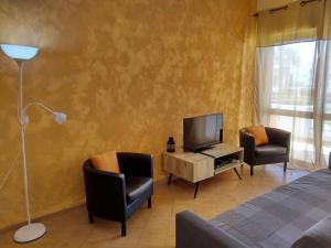 - une chambre avec un lit, deux chaises et une télévision dans l'établissement Apartamento Areias Mar, à Albufeira