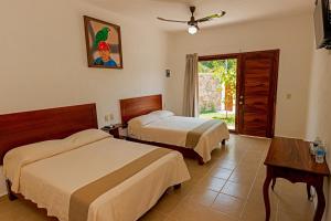 Habitación de hotel con 2 camas y ventana en HOTEL CASA VICTORIA en Zihuatanejo