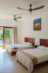 a bedroom with two beds and a ceiling fan at HOTEL CASA VICTORIA in Zihuatanejo