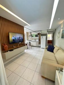 a living room with a couch and a flat screen tv at Nannai Residence Porto Galinhas Praia Muro Alto 101 in Porto De Galinhas