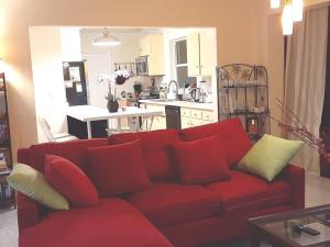 a red couch in a living room with a kitchen at Gorgeous Lakeview Front Lake Osborne in Lake Worth