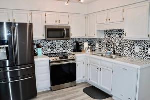 cocina con armarios blancos y nevera negra en Peaceful Family Lake House, en Jacksonville