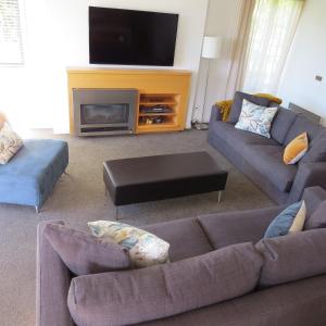a living room with two couches and a flat screen tv at Belvedere Apartments in Wanaka