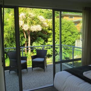 a bedroom with a bed and two chairs on a balcony at Belvedere Apartments in Wanaka