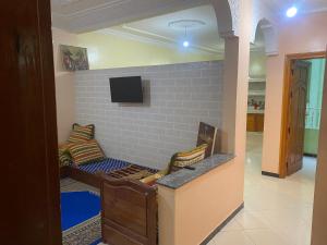 a living room with a couch and a tv on a wall at Appartement Ain Asserdoun in Beni Mellal