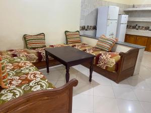 a room with two couches and a table and a kitchen at Appartement Ain Asserdoun in Beni Mellal