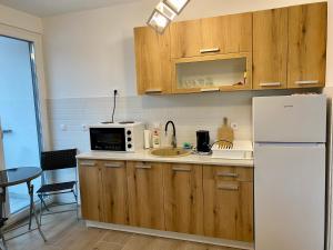 - une cuisine avec des placards en bois et un réfrigérateur blanc dans l'établissement Apartman Anastasija Jezero, à Divčibare