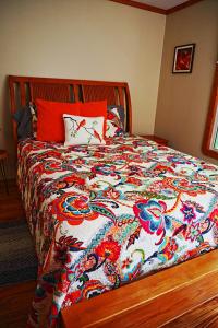 a bed with a colorful comforter and pillows on it at Our Private Wooded Cabin in Chatham