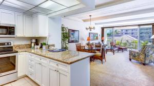 a kitchen with white cabinets and a living room at Maui Westside Presents- The Whaler 319 in Lahaina