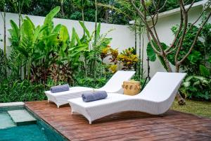 2 sedie bianche sedute su una terrazza di legno accanto alla piscina di Villa Pulau I, 1BR Luxury Private Villa with Pool in North of Bali, Pemuteran, within Walking Distance to a Wild Beach a Buleleng