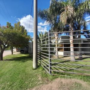 una cerca blanca frente a una casa con palmeras en Casa Olivia en Villa María