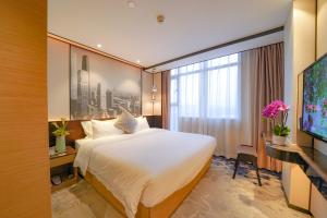 Pokój hotelowy z dużym łóżkiem i telewizorem w obiekcie Guangdong Baiyun City Hotel w Guangzhou