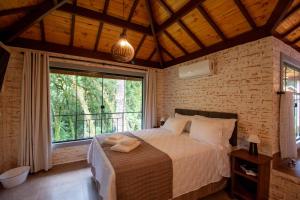 a bedroom with a bed and a large window at Vivendas de Monte Verde in Monte Verde