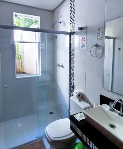 a bathroom with a shower and a toilet and a sink at Pousada Della Vegas in Serra Negra