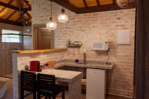 a kitchen with a sink and a counter with chairs at Vivendas de Monte Verde in Monte Verde