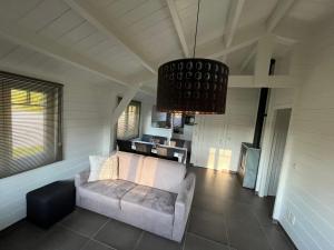 a living room with a couch and a chandelier at Welkom bij Mario, Een charmante Chalet gelegen aan een vijver in bosrijke omgeving waar je tot rust kan komen. 