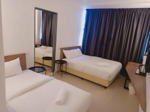 a hotel room with two beds and a mirror at T Hotel Anggerik in Alor Setar