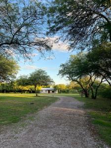 un camino de grava en un parque con árboles y un edificio en Tu alojamiento en Santiago del Estero en Santiago del Estero