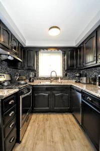 a kitchen with black cabinets and a sink and a window at King Bed! Quiet Pittsburgh Home! Close to City! in Pittsburgh