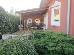 un porche delantero de una casa con arbustos en Evelyn Apartman, en Bük