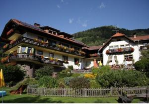 une grande maison avec une clôture devant elle dans l'établissement Das kleine Familienhotel Koch, à Eisentratten