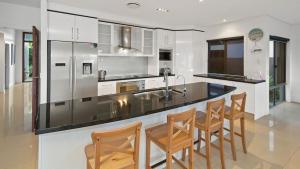 a kitchen with a bar with chairs and a counter top at Luxury waterfront house close to Theme Parks and shops in Gold Coast