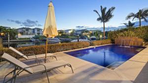 a swimming pool with two chairs and an umbrella at Luxury waterfront house close to Theme Parks and shops in Gold Coast