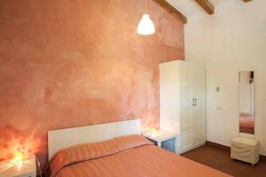 1 dormitorio con 1 cama con pared de color naranja en Come In Sicily La Pietra Monaca, en Acireale