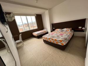 um pequeno quarto com uma cama e uma janela em Hotel Marialu em Ocaña