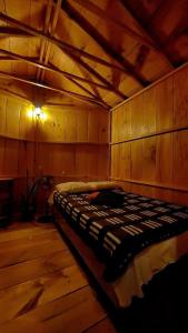 a bed in a room with a wooden wall at Tipis Ya' in San Pedro La Laguna