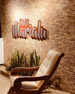 ein Schild an einer Ziegelmauer mit zwei Stühlen in der Unterkunft Hotel Marialu in Ocaña