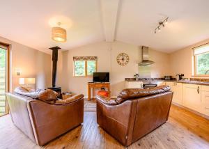 a living room with two leather chairs and a kitchen at Meadows End Lodges in Cartmel