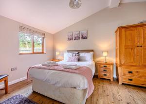 a bedroom with a large bed and a dresser at Meadows End Lodges in Cartmel