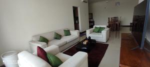 a living room with white couches and green pillows at Asian Residencies @ Trillium, Colombo 7 in Colombo