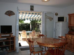 een keuken met een tafel en stoelen en een glazen schuifdeur bij Maison La Tranche-sur-Mer, 3 pièces, 4 personnes - FR-1-22-209 in La Tranche-sur-Mer