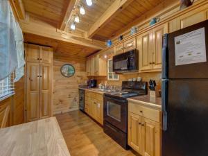 a kitchen with wooden cabinets and a black refrigerator at Macys Hideaway, 1 Bedroom, Hot Tub, WiFi, Sleeps 7 in Sevierville