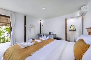 a bedroom with a large white bed with two white bows at BB Garden Resort in Canggu