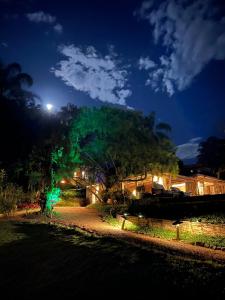 Una casa iluminada por la noche con un árbol en Pousada Boutique Itaipava, en Itaipava