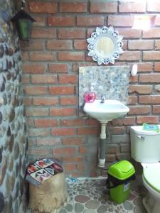 a brick walled bathroom with a sink and a toilet at Tony's House Eco Hostel in Huaraz