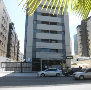 dos autos estacionados frente a un edificio alto en NA BEIRA MAR DE PAJUCARA - EDIFICIO NEO 2 - TEM VARANDA - VISTA LATERAL DO MAR- APARTAMENTO COM 02 QUARTOS - AVENIDA DOUTOR ANTONIO GOUVEIA 1081- CONSUMO ELETRICO É PAGO No CKECK-OUT 1KWH É 1,35 REIAS, en Maceió