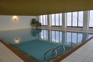 a large swimming pool in a building with windows at Apartments Chesa Guardaval in Surlej