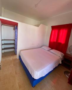 1 dormitorio con cama blanca y cortinas rojas en Casa de Heidi, en Puerto López