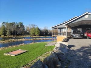 a house with a car parked next to a lake at Marshmallow home in Gilmour
