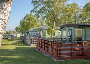 una fila de casas verdes con una valla de madera en Wild Rose Holiday Park en Colby