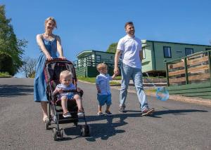 una mujer y un hombre y un niño en un cochecito en Wild Rose Holiday Park en Colby