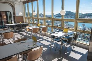 a restaurant with tables and chairs and large windows at Hotel Kenny Yeosu in Yeosu