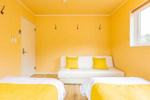 um quarto amarelo com um sofá com duas almofadas amarelas em ふくろう庵-白浜- em Shirahama