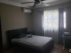 sypialnia z łóżkiem z wentylatorem sufitowym i oknem w obiekcie Popsie's Paradise w mieście Jarbang
